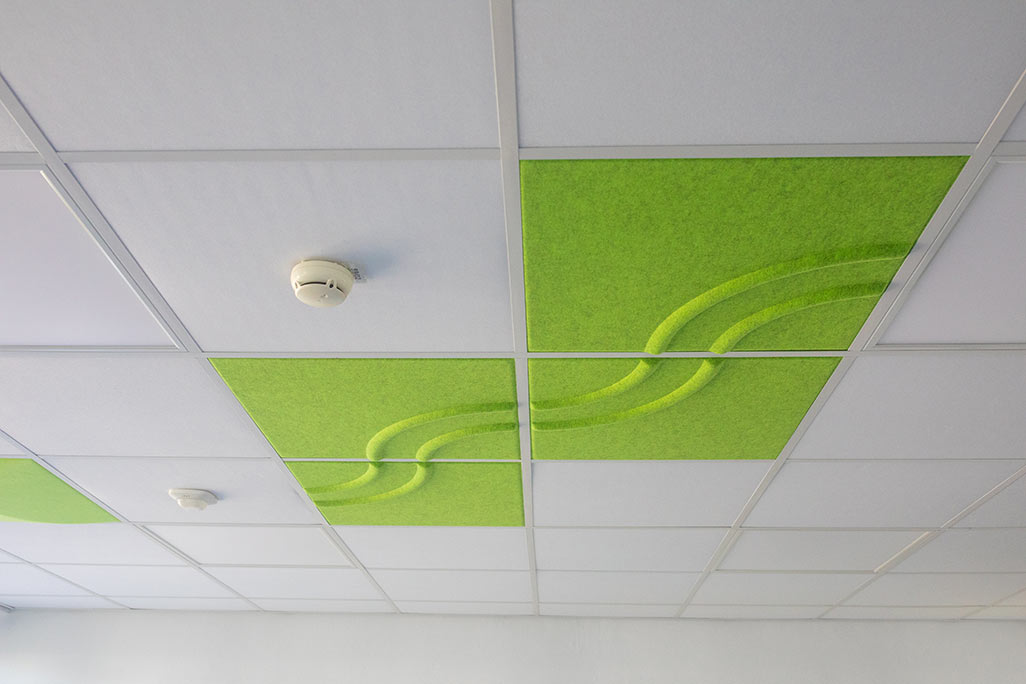 Section of a standard grid ceiling with inlaid soni COMFORT SD acoustic absorbers in white and soni COLOR Design in green.