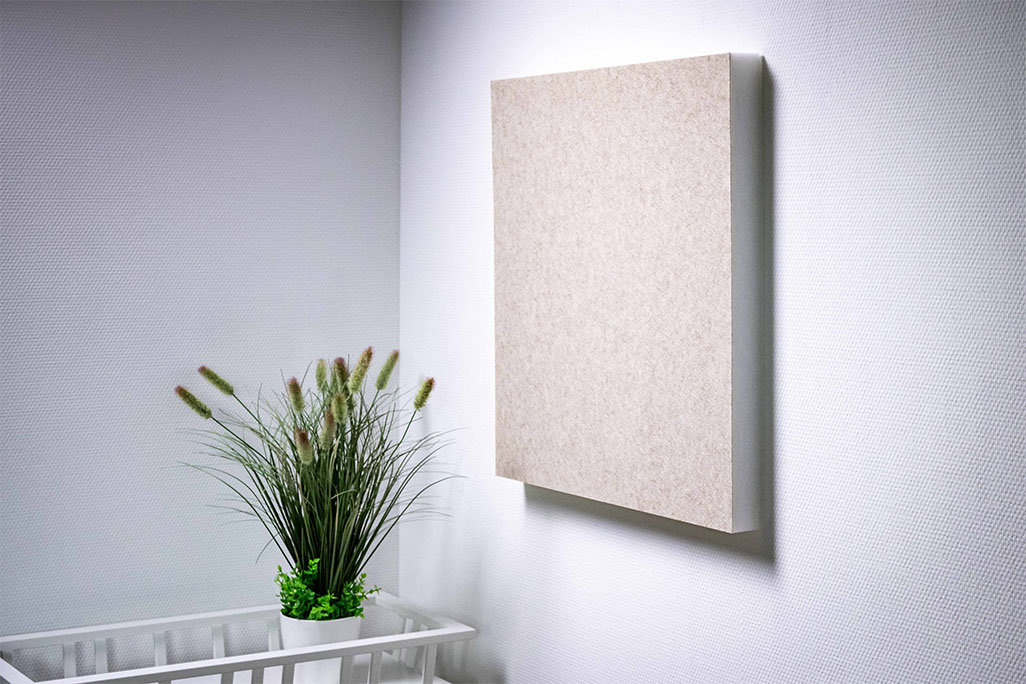 Light-colored wall with a square acoustic element with Greiger felt surface, next to it a shelf with a green grass plant