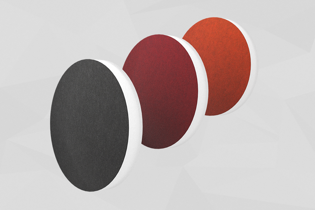 Three sound absorbers in the shape of a circle (soni ELEMENT CIRCLE) standing one behind the other in the colors anthracite, red and orange against a grey background