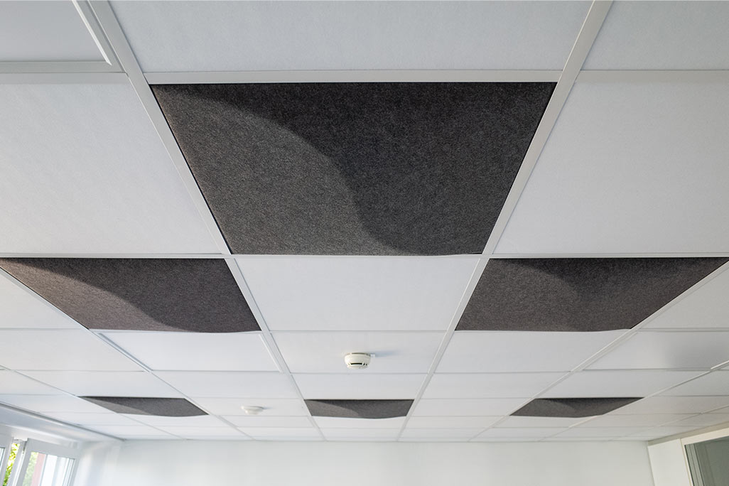 Section of a standard grid ceiling with inlaid soni COMFORT SD acoustic absorbers in white and soni COLOR Design in anthracite.