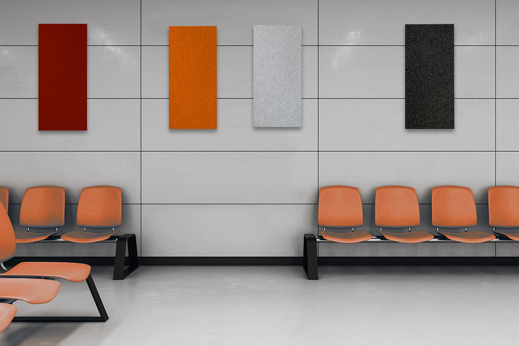 Waiting room with orange chairs and a wall showing four rectangular acoustic elements in red, orange, light gray and anthracite