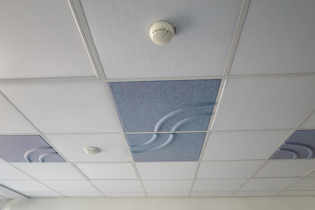 Section of a standard grid ceiling with inlaid soni COMFORT SD acoustic absorbers in white and soni COLOR Design in blue.