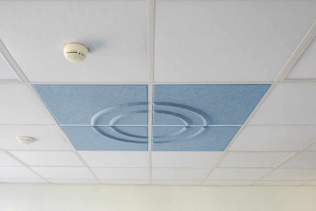 Section of a standard grid ceiling with inlaid soni COMFORT SD acoustic absorbers in white and soni COLOR Design in blue.